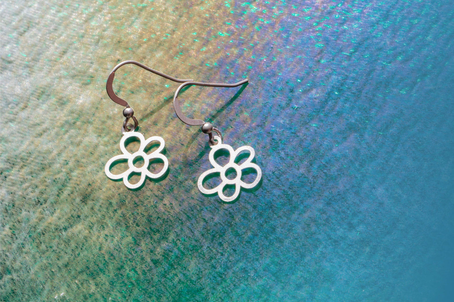 a pair of stirling silver earrings shaped as a single daisy flower
