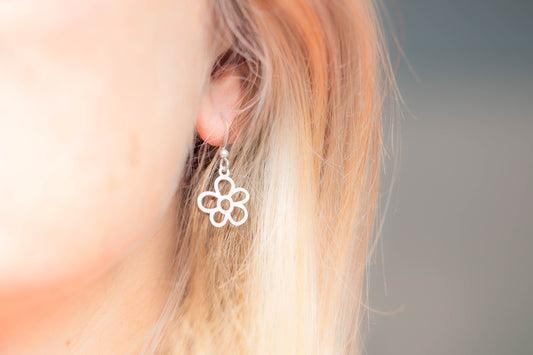 A single elegant daisy flower shaped earring worn by model