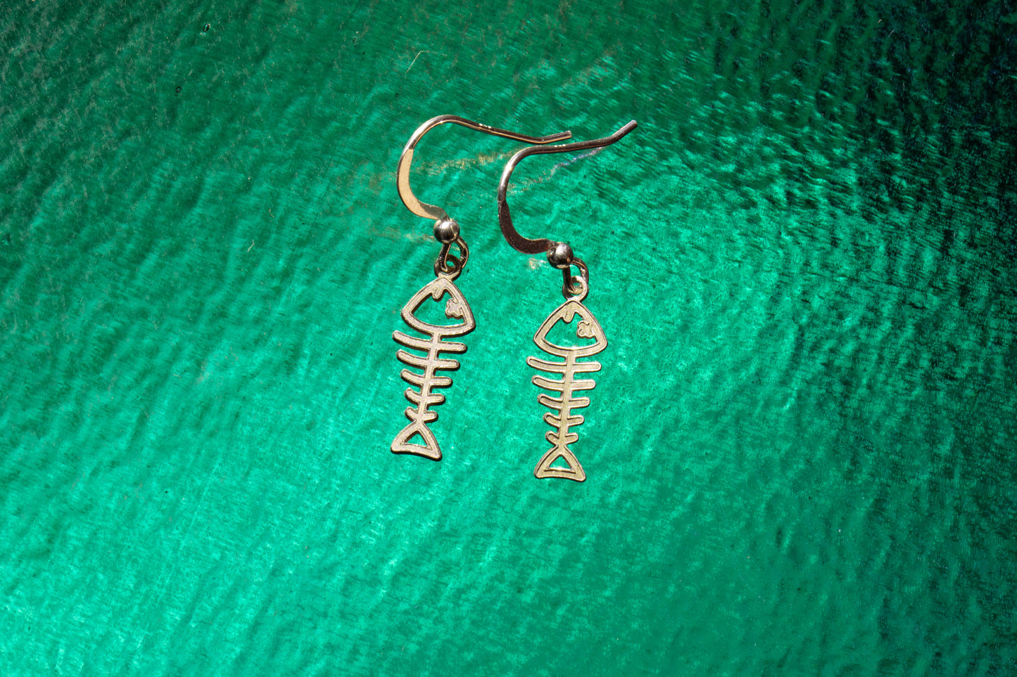 a pair of sterling silver earrings shaped as fish skeletons