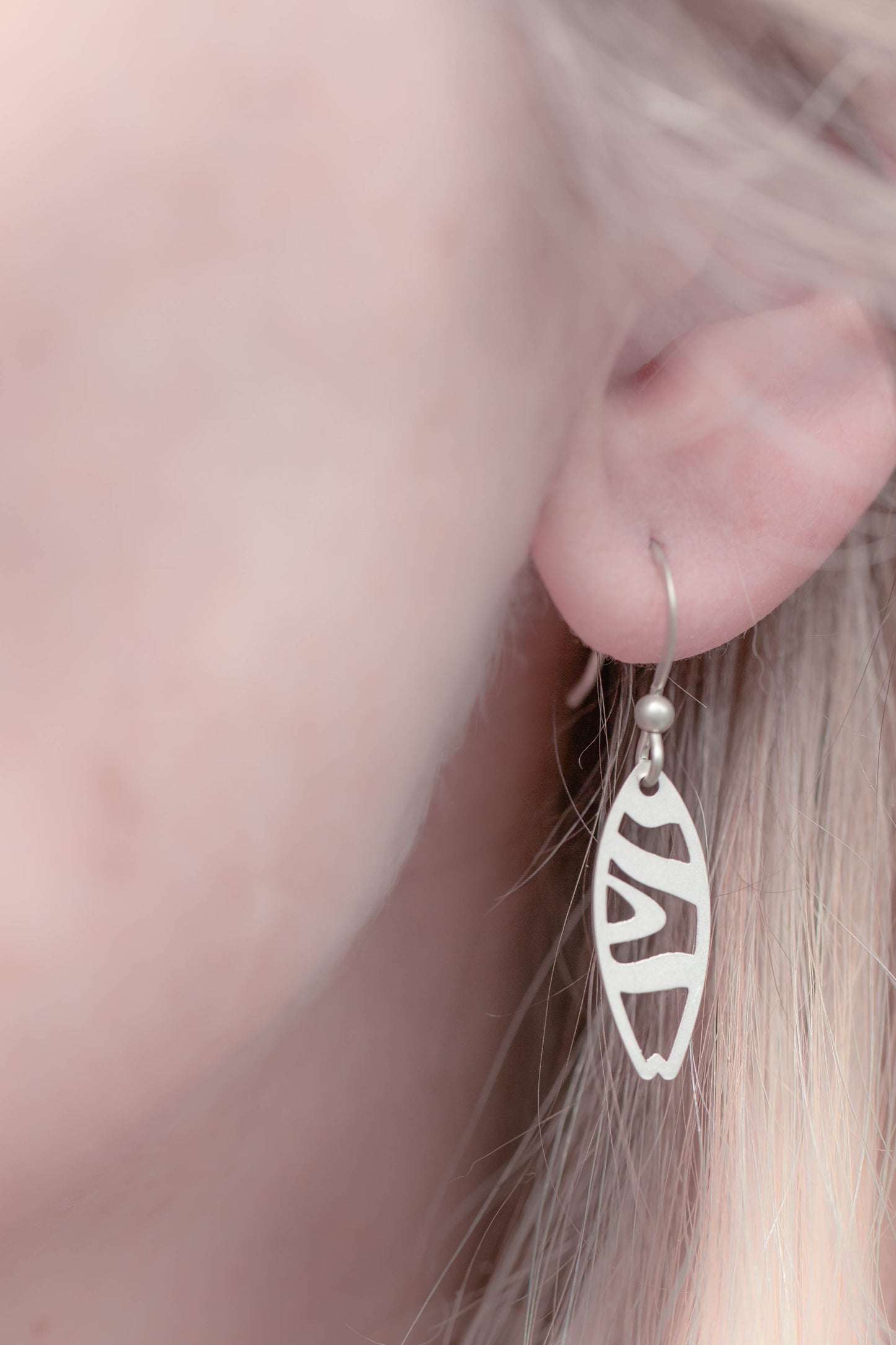 a single sterling silver tiger striped surfboard earring worn by model