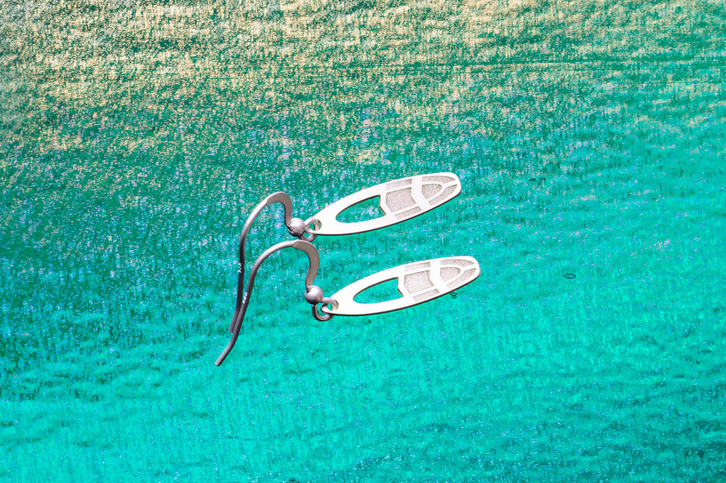 a pair of unique earrings shaped as a small surfboard