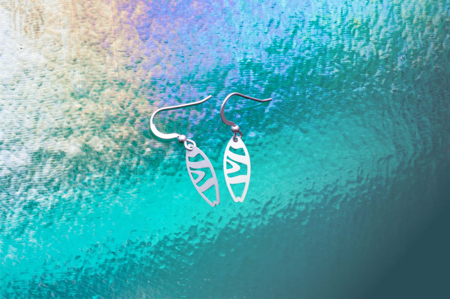 two sterling silver earrings in front of a glowing water effect