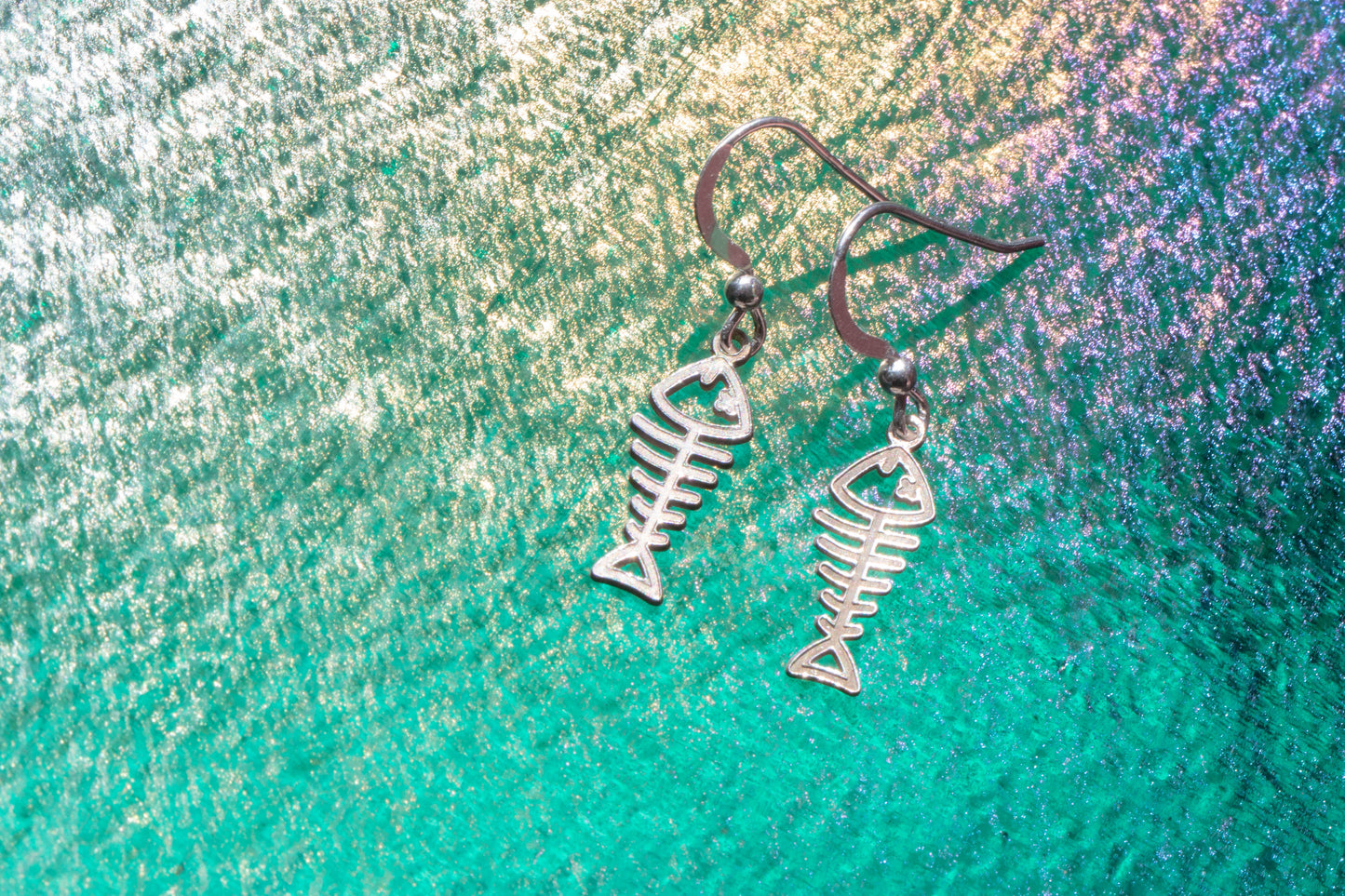 sterling silver earrings shaped liked fish shining on an emerald sea background