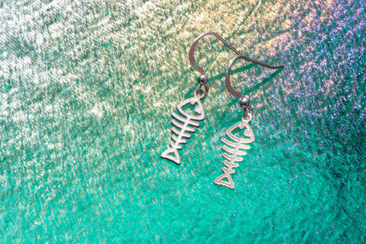 sterling silver earrings shaped liked fish shining on an emerald sea background