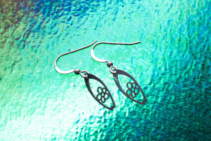 a pair of daisy flower surf inspired earrings on a breaking wave effect background