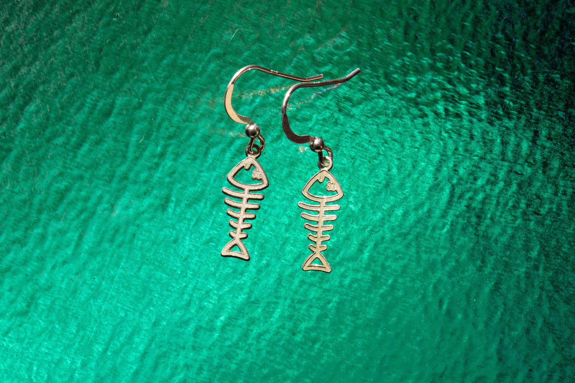 a pair of sterling silver earrings shaped as fish skeletons