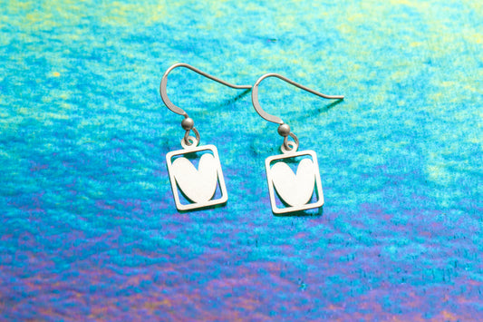 a pretty pair of silver earrings designed around a  heart locked in a  box