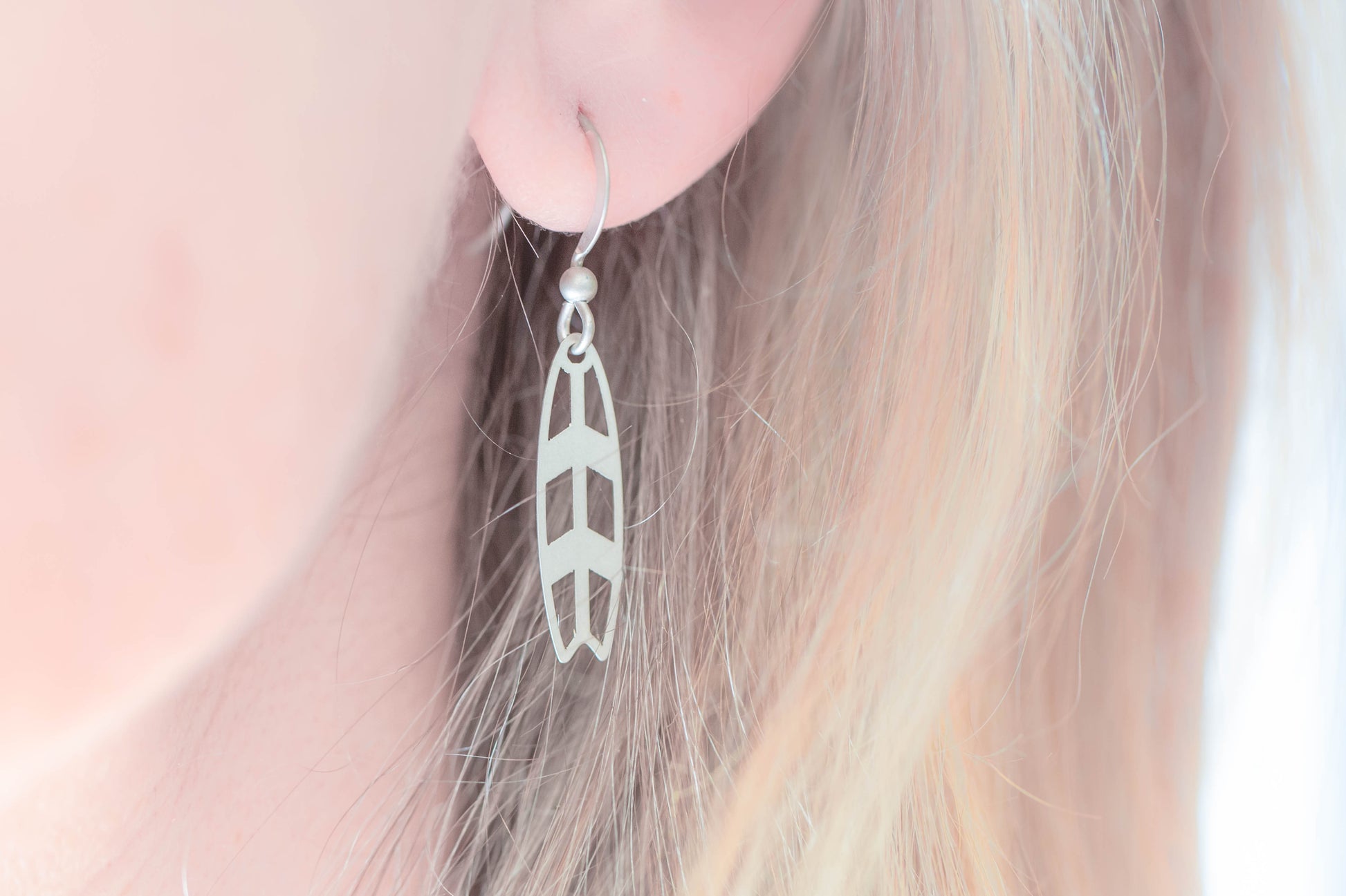 A single sterling silver earring shaped as a surfboard worn by model