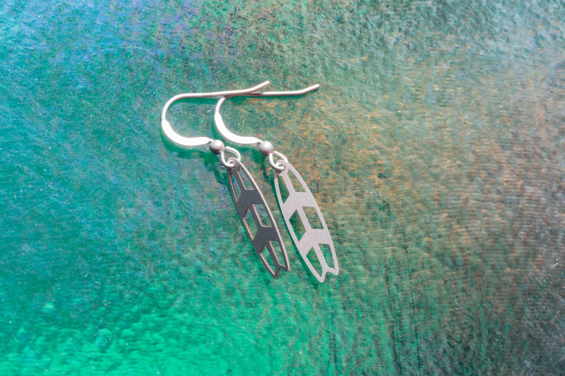 a pair of stirling silver earrings on a greet shimmering background